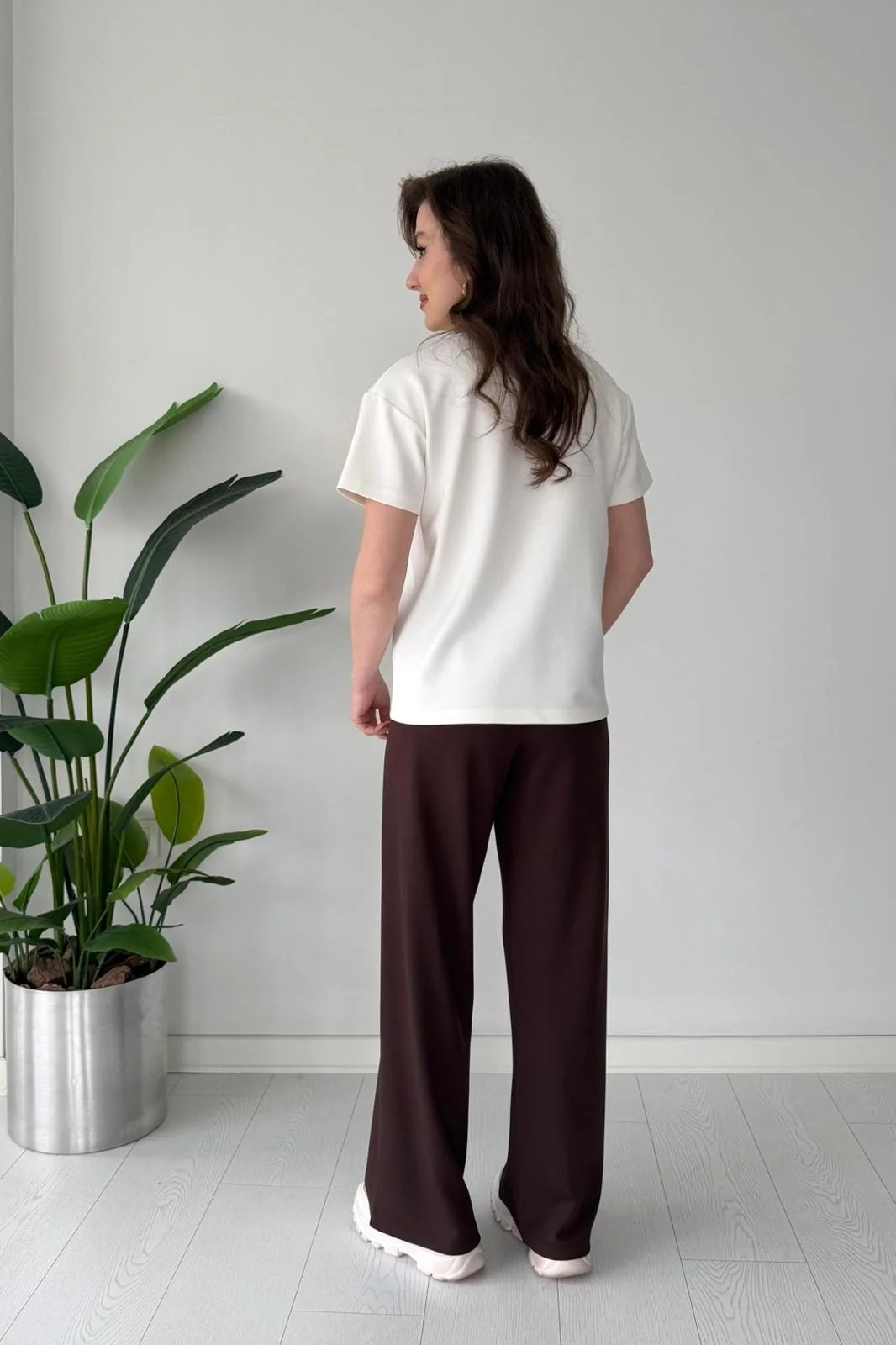 Printed cord set with white shell graphic T-shirt and dark brown wide-leg pants, back view
