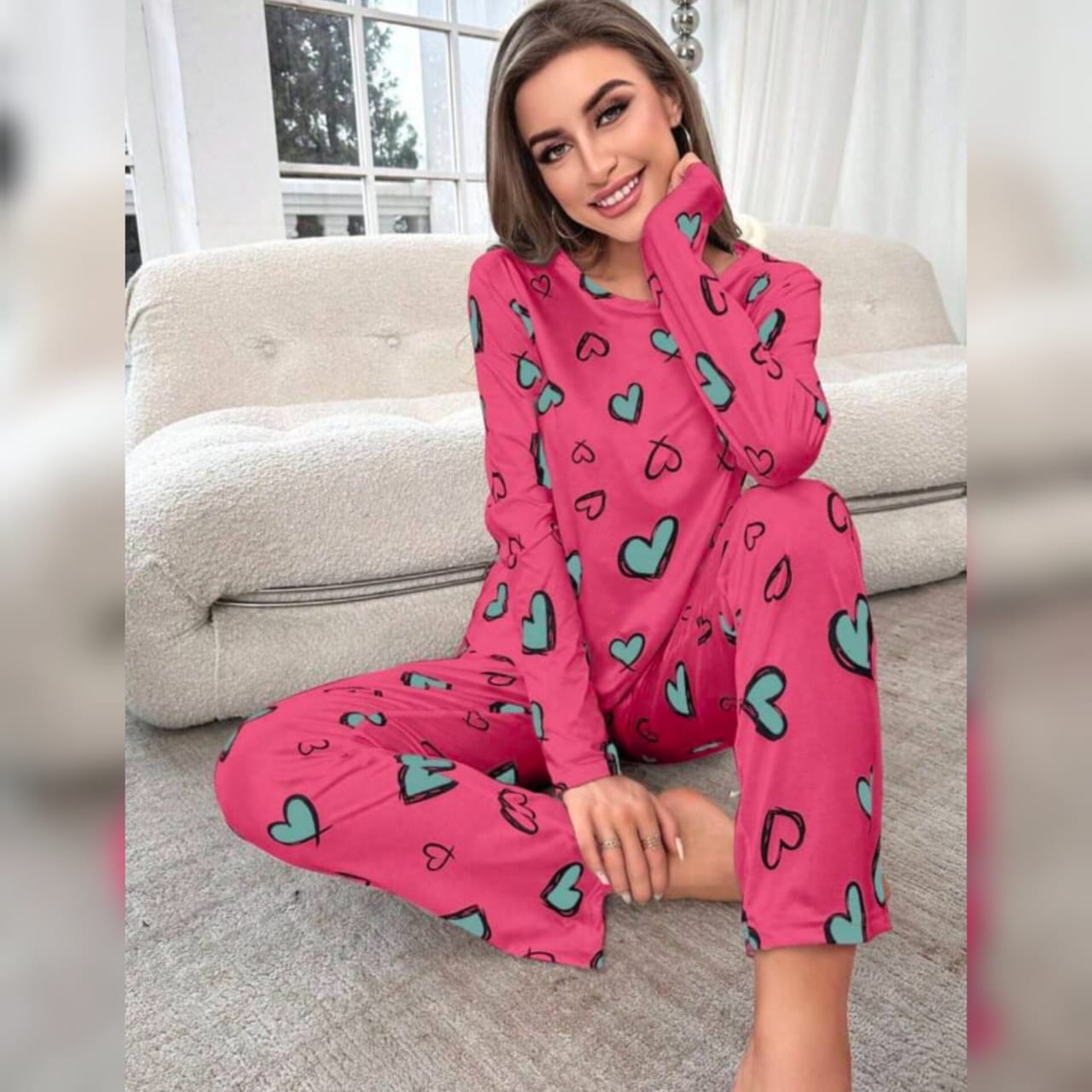 Pink heart-print long-sleeve PJ set with matching long pants, seated pose