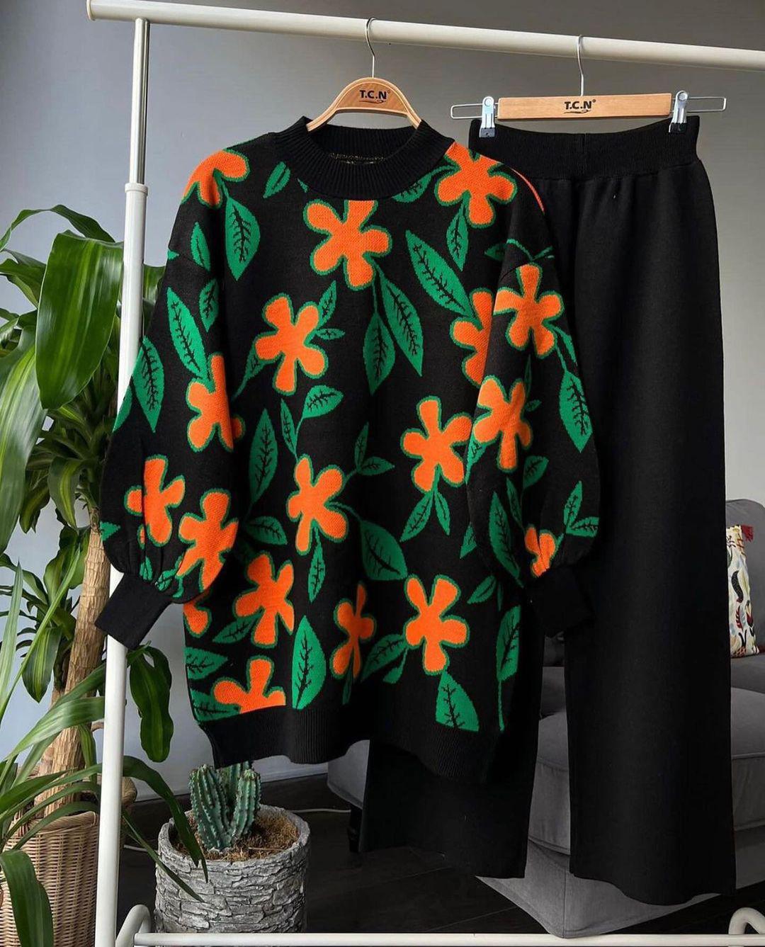 Black leaf knit sweater with multicolor red and orange floral motifs and black trousers