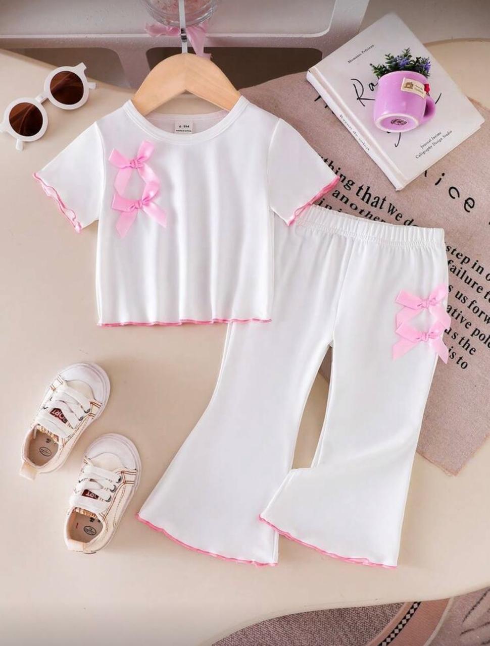 White baby outfit set with pink ribbon bows on top and pants with pink trim