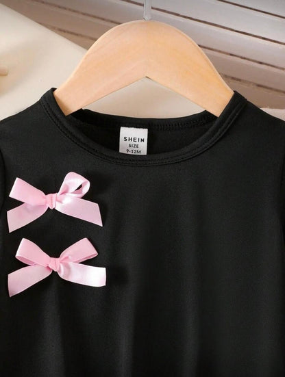 Black short-sleeve top with two pink ribbon bows and crew neckline