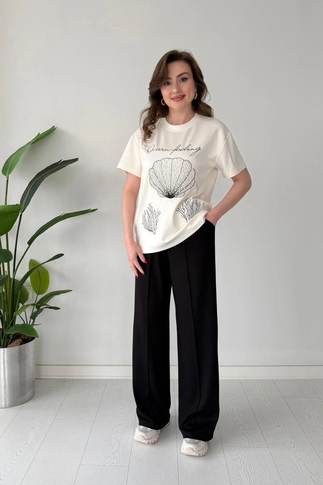 Printed cord set with white shell graphic T-shirt and black wide-leg pants, slight side pose