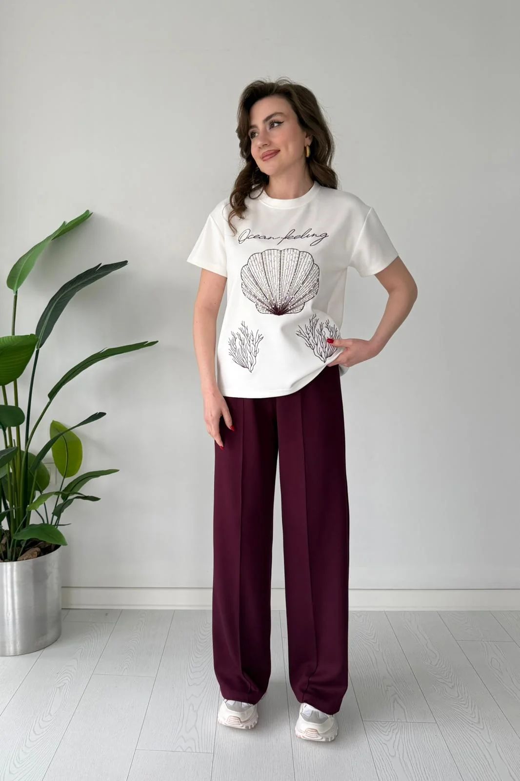 Printed cord set with white shell graphic T-shirt and maroon wide-leg pants, full body