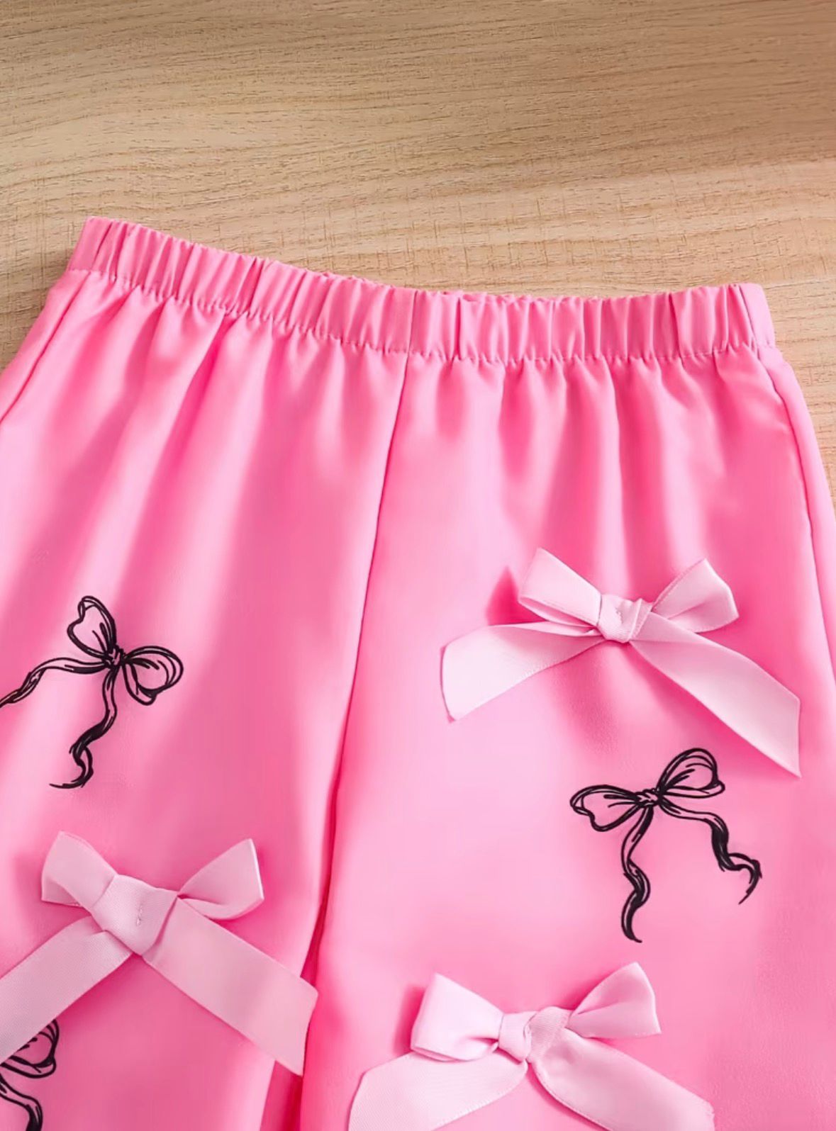 Pink bow set shorts with elastic waist and white ribbon bows, black silhouette accents