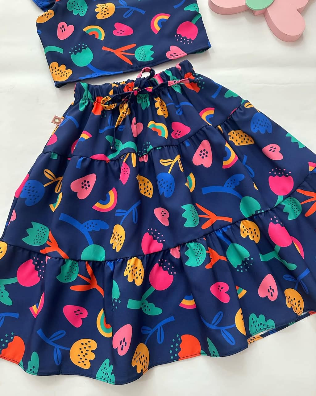 Navy tiered skirt with elastic waistband and colorful fruit and rainbow print