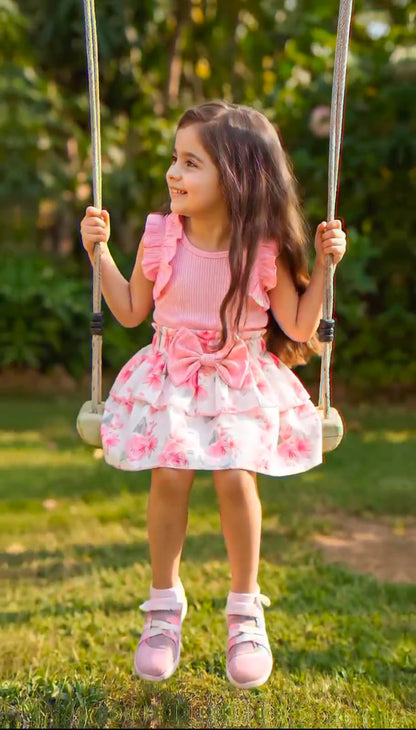 Girls' pink ruffle dress with floral tiered skirt, standing side view