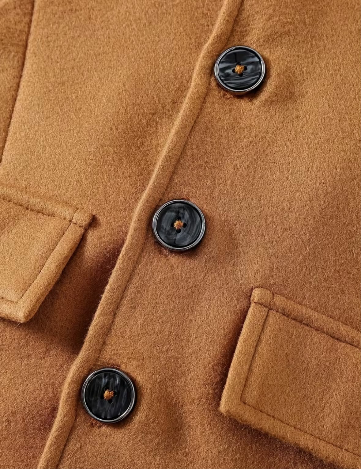 Camel coat fabric close-up with round buttons and chest pocket