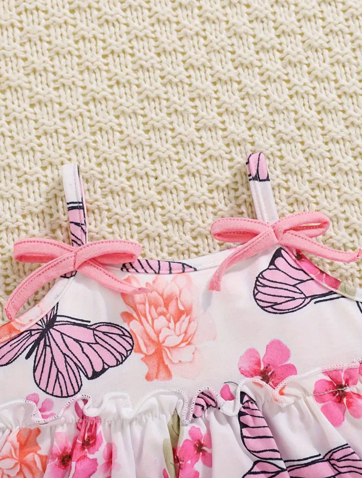Floral and butterfly print top with pink ribbon shoulder ties and ruffle trim