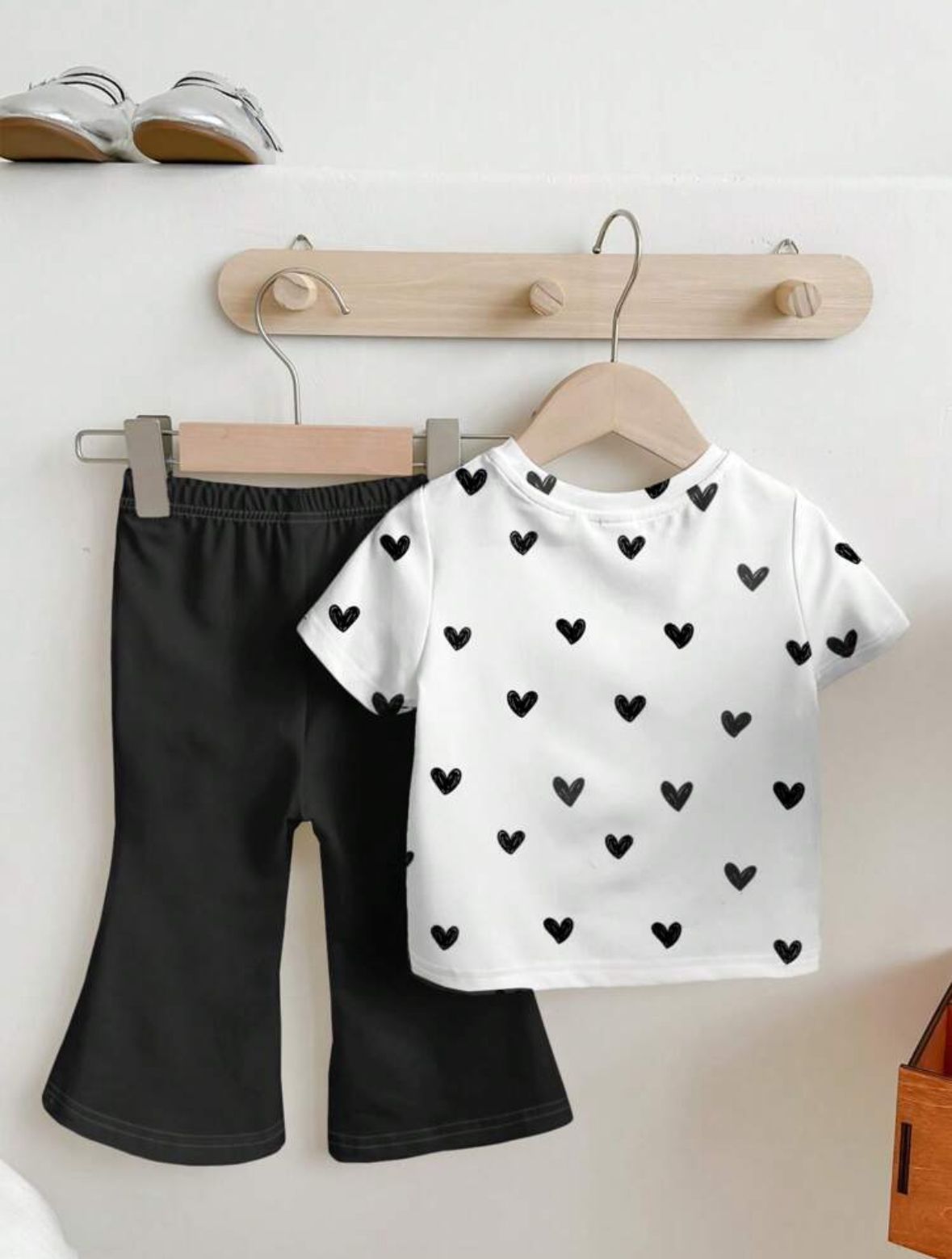 Kids two-piece set: white heart-print T-shirt and black trousers on hangers