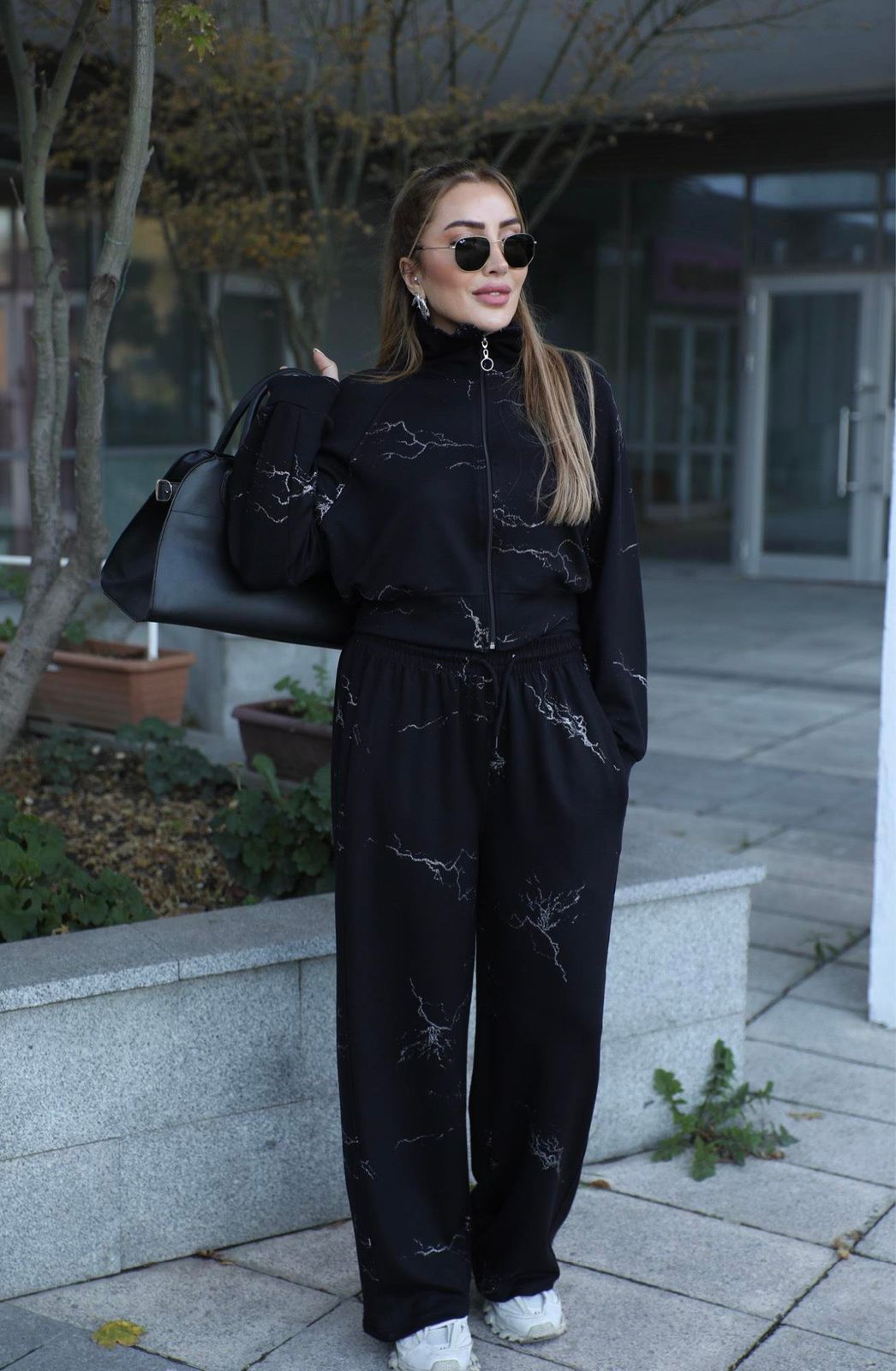 Black two-piece outfit: draped zip jacket and wide-leg pants with scattered line motifs