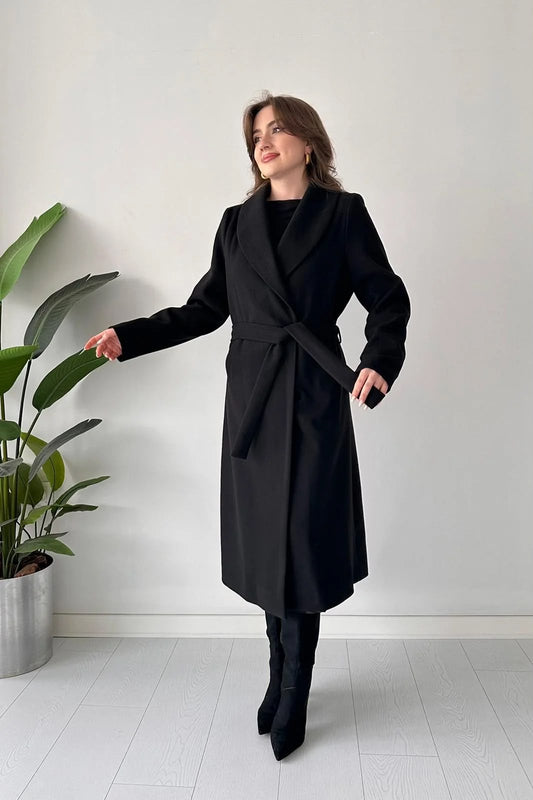 Black long belted coat with wrap lapels and waist tie, standing pose.